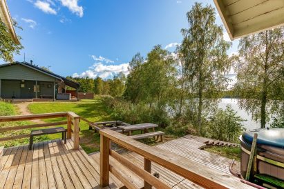 View from the terrace of Aulanko Lakeside's lakefront sauna. In the foreground, there is a wood-heated hot tub and a fireplace, and on the main building's terrace, there is an electric heated jacuzzi.