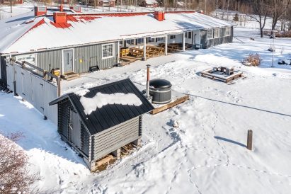 The front yard of Aulanko Grand Villa. In the foreground, a woodshed and a wood-fired hot tub.