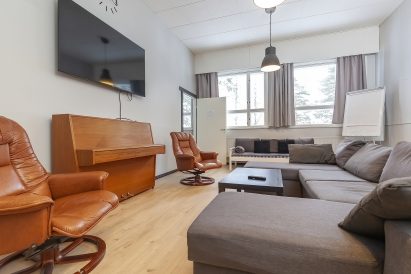 In the main hall of Räyskälä Grand Villa, there are two widescreen televisions and a piano. The sofas can also be used as extra beds.